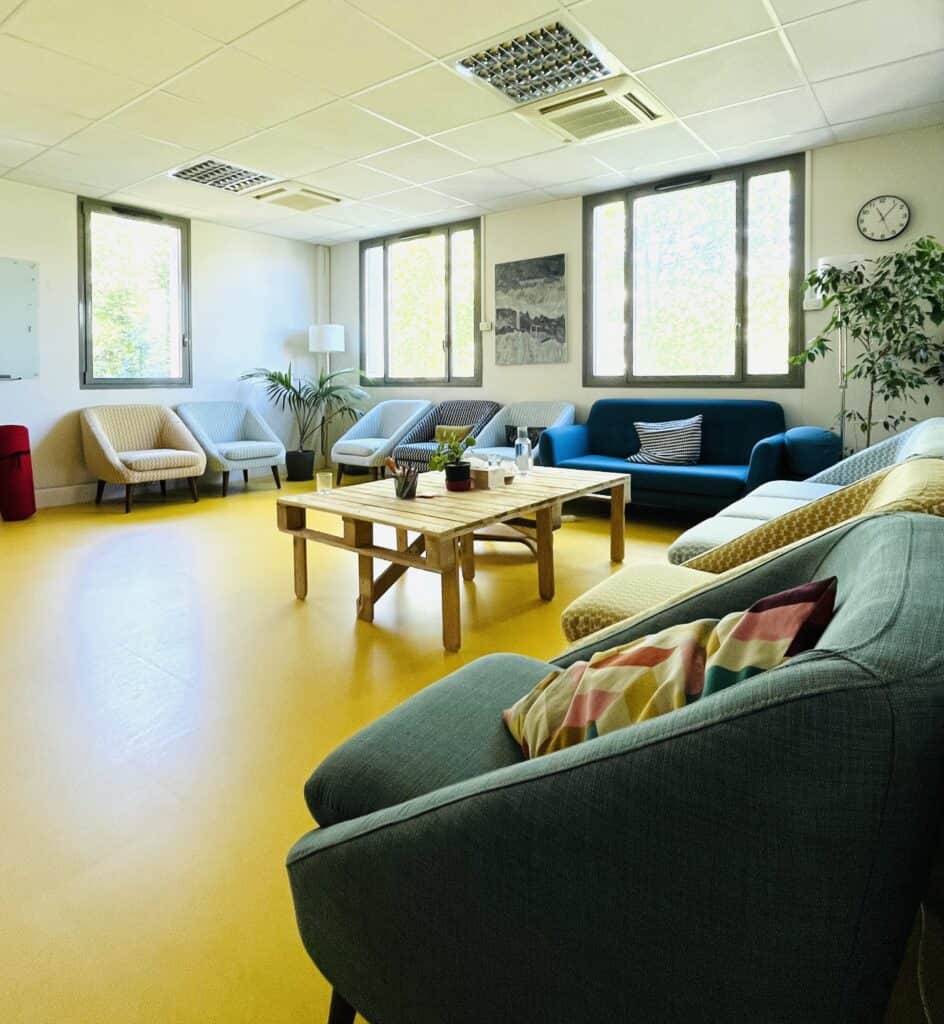 Salle de formation moderne avec canapés confortables et grande luminosité.
