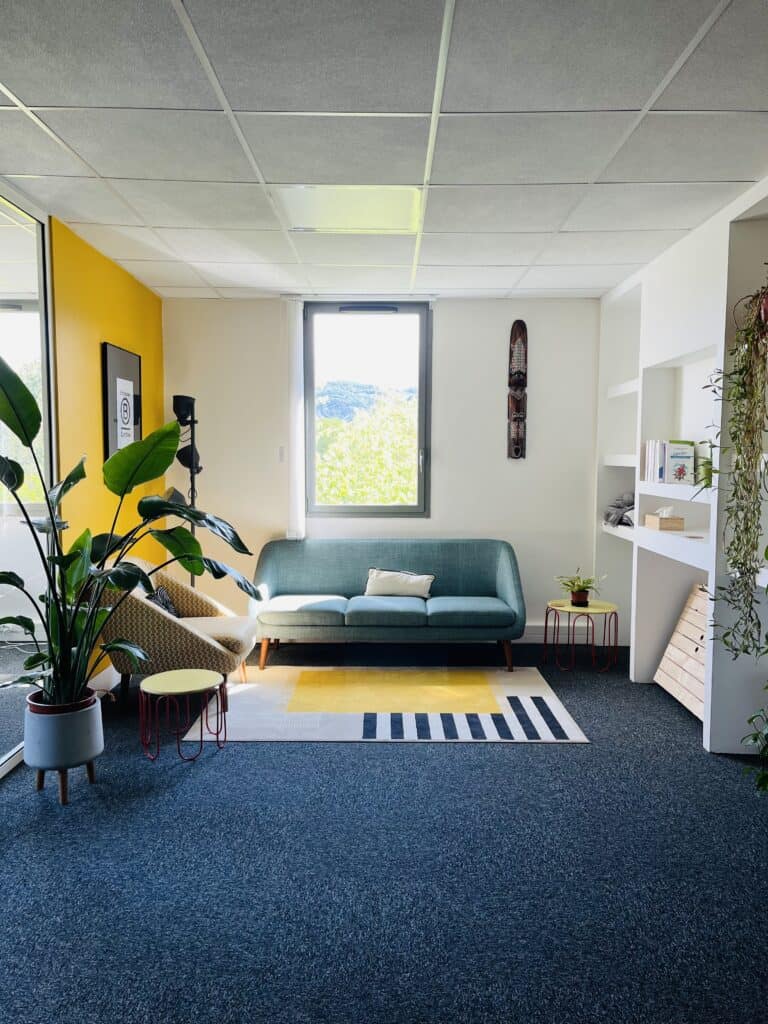 Salle de coaching moderne avec canapé, plantes et décoration épurée.
