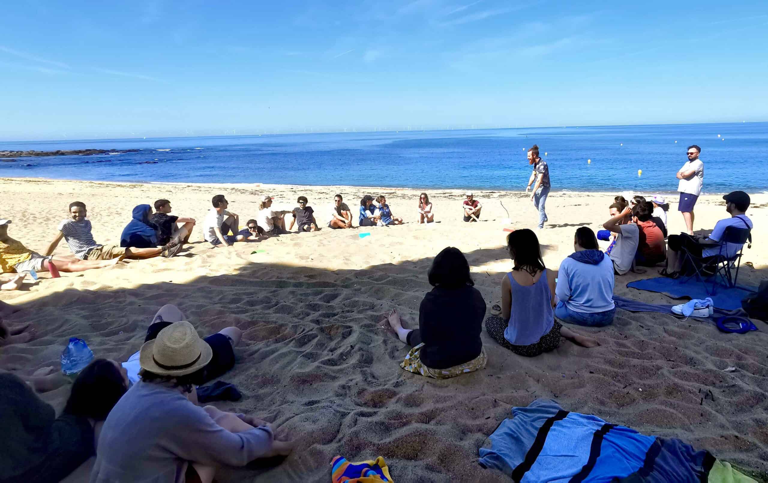 Groupe en plein coaching organisationnel sur la plage avec vue sur la mer.