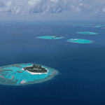 Vue aérienne d'une île tropicale entourée d'eau turquoise.