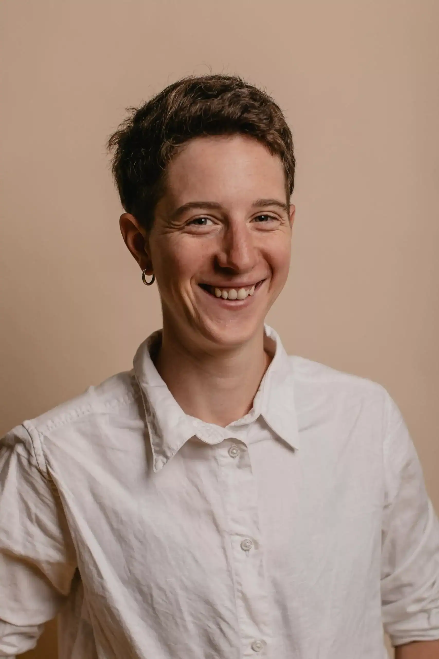 Femme souriante avec une chemise blanche et boucle d'oreille.