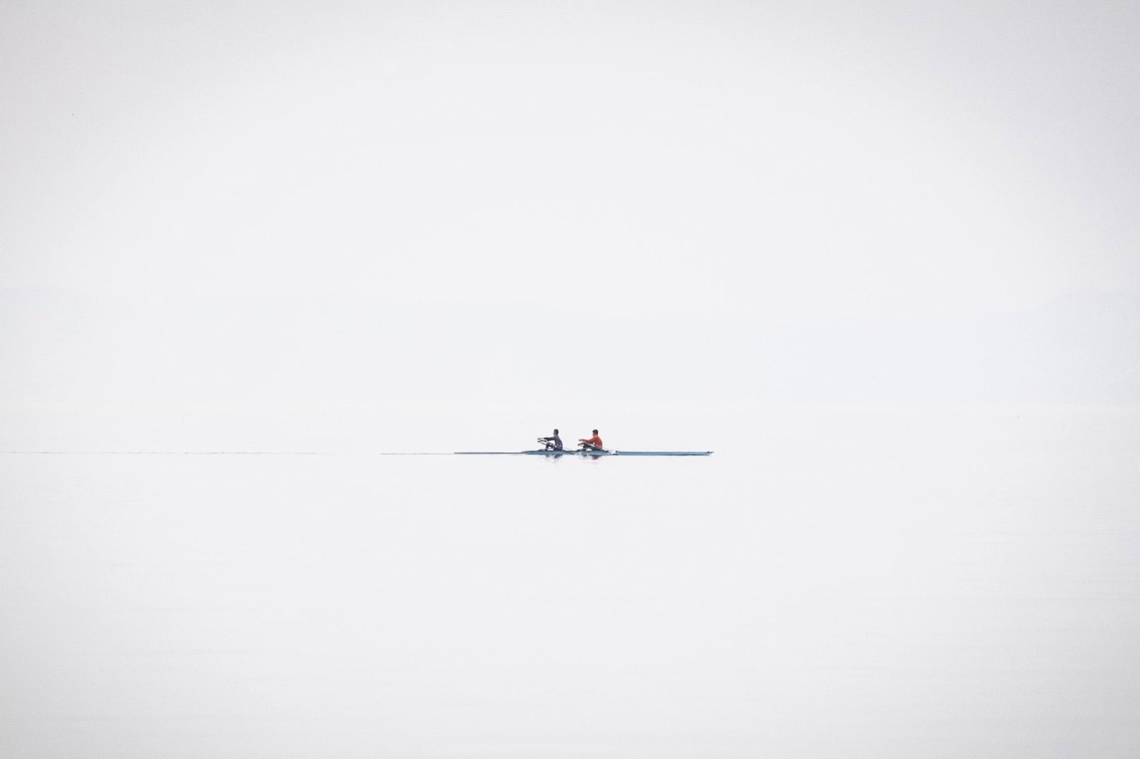 Deux kayaks sur un lac calme avec un fond blanc.