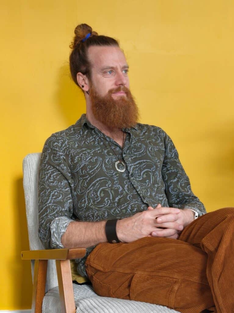 Homme avec barbe et cheveux en chignon lors d'une séance de coaching.