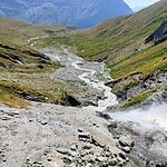 Source d'eau en montagne avec rivière et vallées verdoyantes.