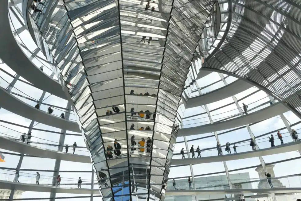 Vue intérieure d'une structure en verre et acier avec des visiteurs.